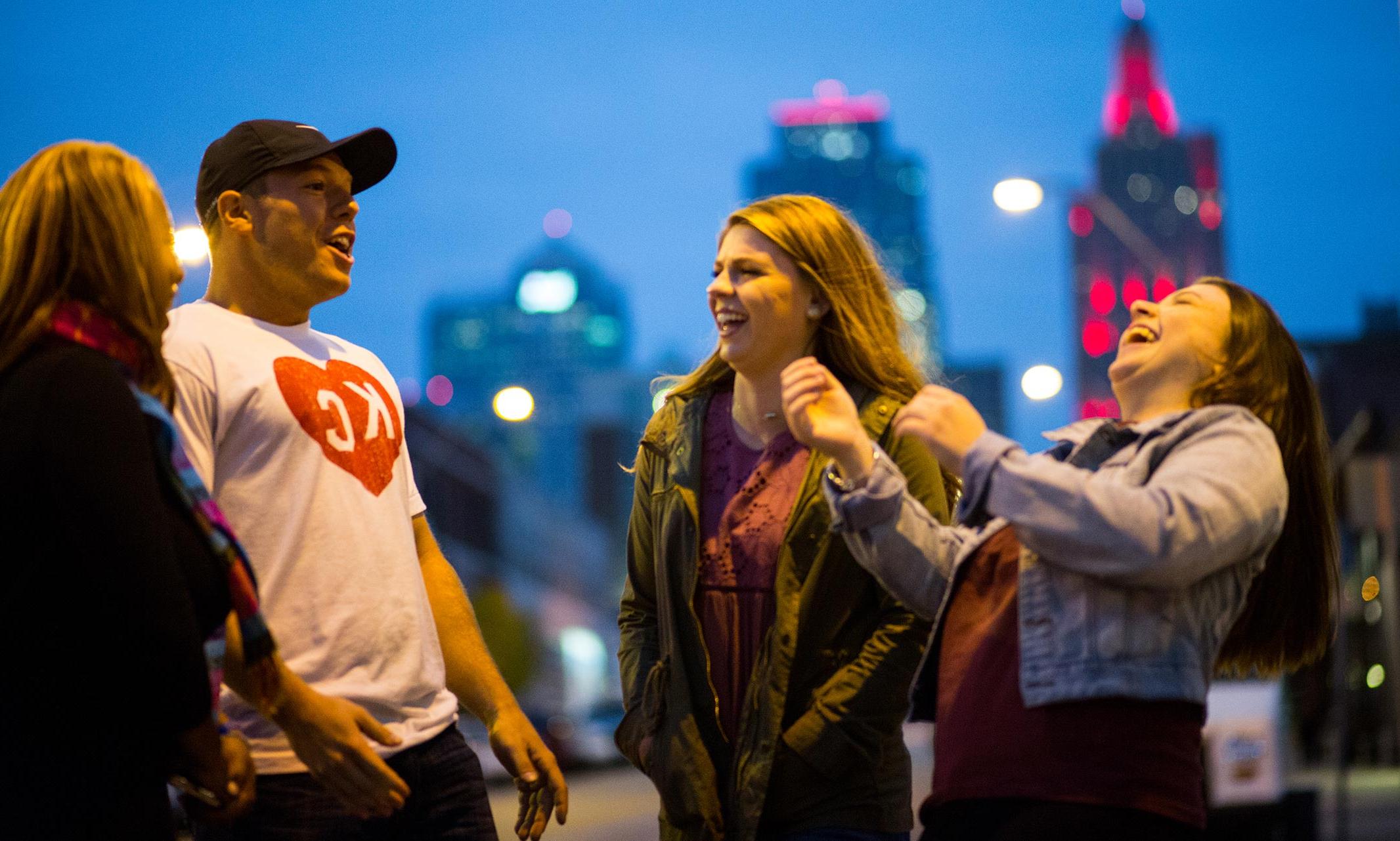 Four people having a joyful conversation with Kansas City skyline in the background