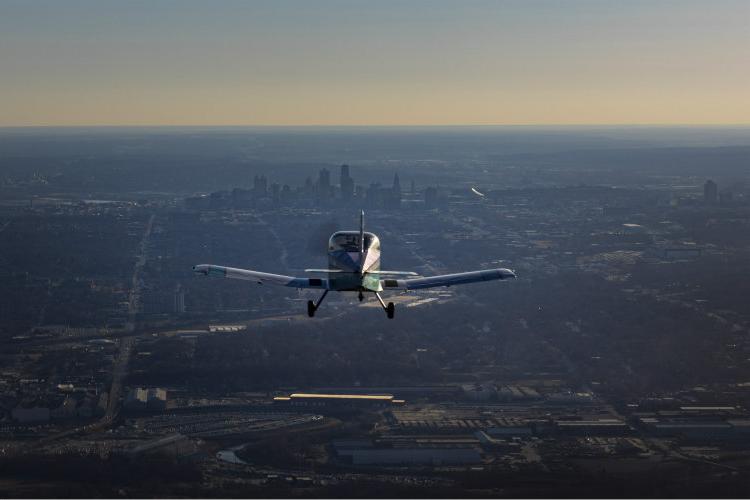 An airplane in flight with Kansas City skyline in background