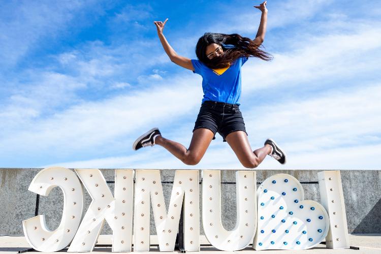 student jumping in front of I heart UMKC sign