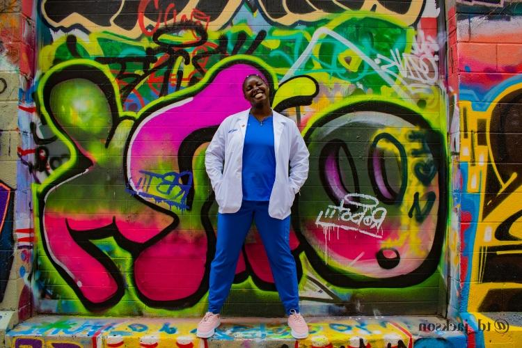 可可Ndipagbor微笑地站在一幅彩色壁画前