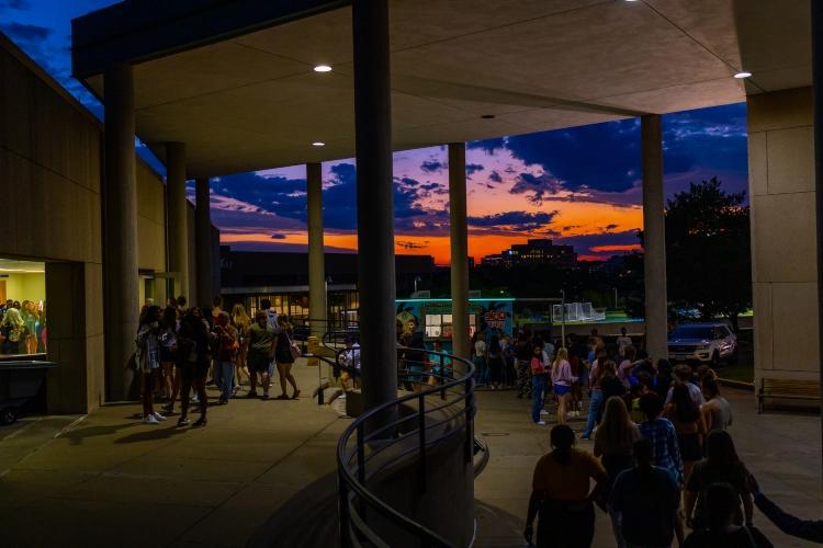 Students fill the walkway behind the Atterbury Student Success Center with the sun setting in the background at Late Night with the Greeks