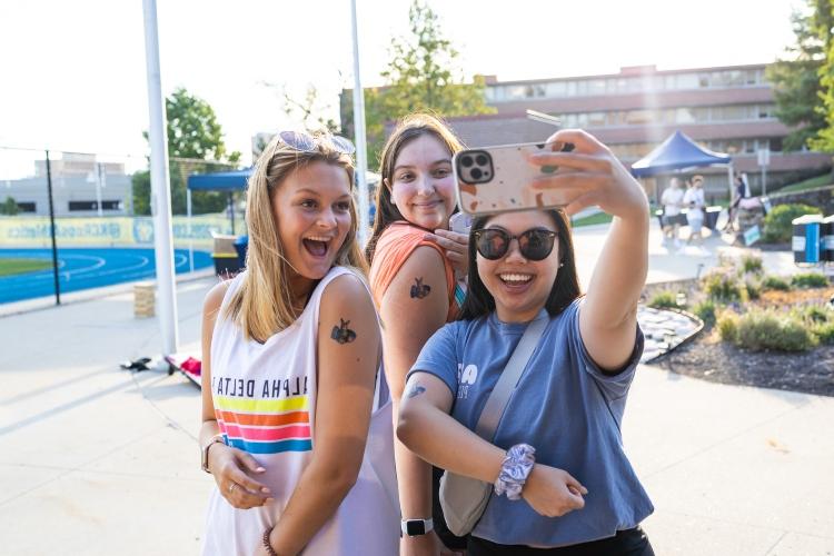 three students with Roo stickers on their arms take a selfie
