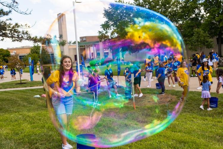 A student smiles with a large bubble in front of her