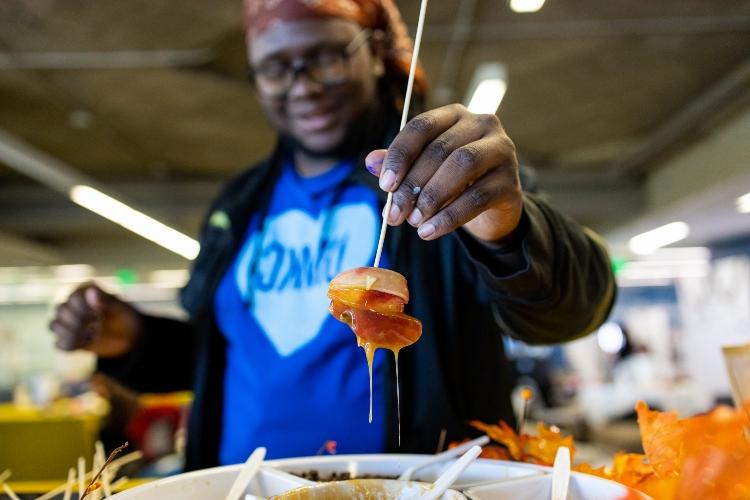 A student in a UMKC heart t-shirt holds an object that has just been dipped in liquid