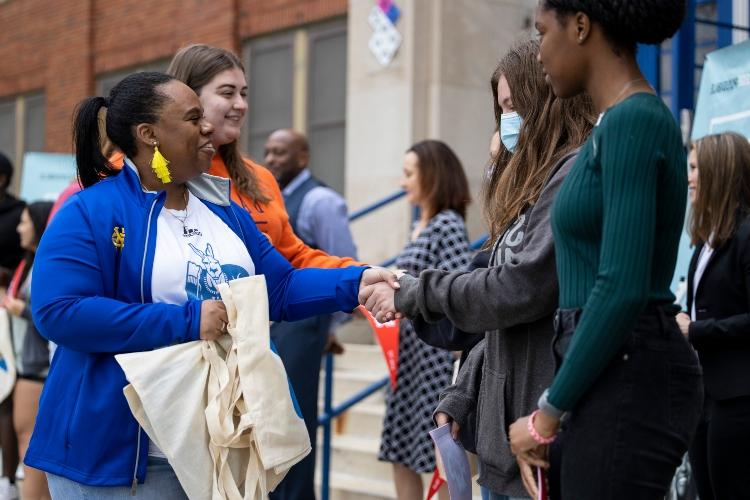 一名身着堪萨斯大学校服的女子与一名学生握手 
