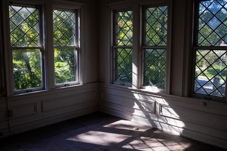 房间的一角，每边都有大窗户. 阳光明媚，窗外绿树成荫.