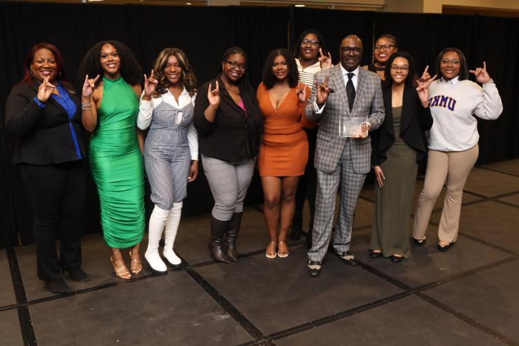 Bob Kendrick stands with students from the African American Student Union with all holding a Roo Up hand gesture