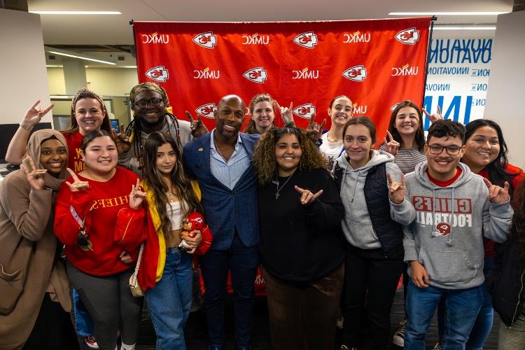 UMKC students spending time with Kansas City Chiefs Ramzee Robinson and Rooing Up in front of the UMKC and Chiefs back drop 